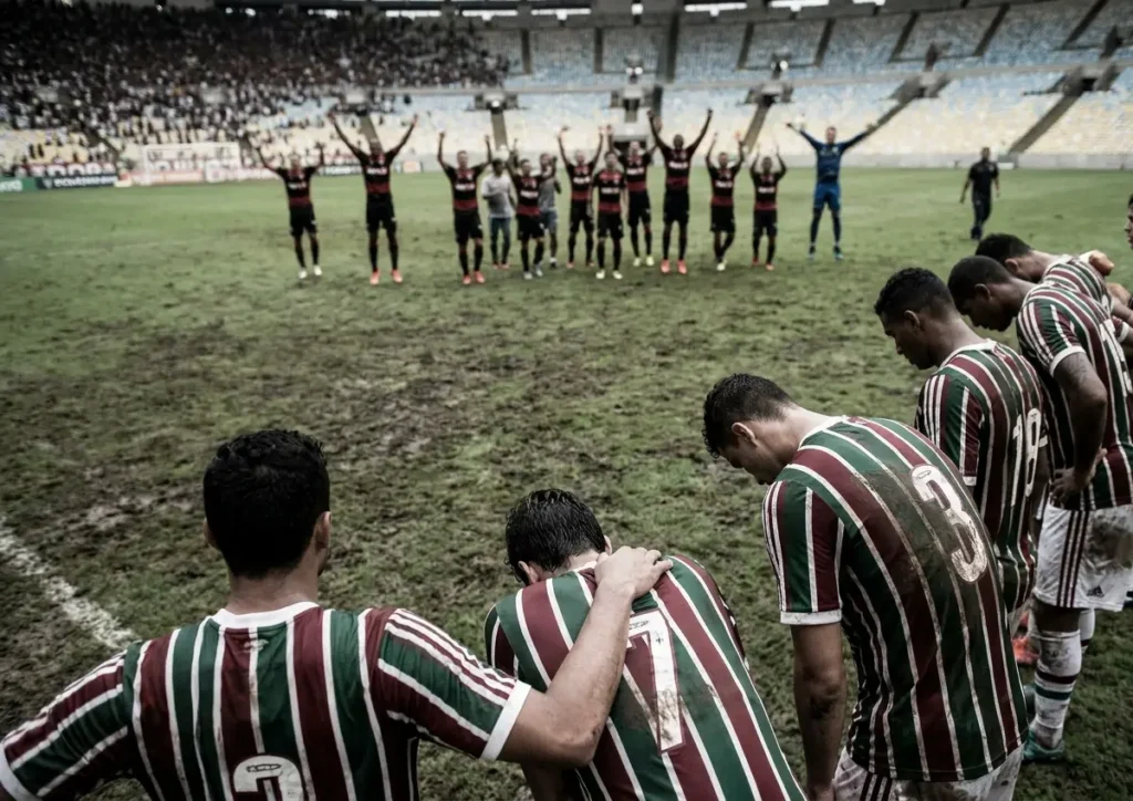 Jogadores do Fluminense de costas cabisbaixos e jogadores do Vitória comemorando ao longe no Maracanã
